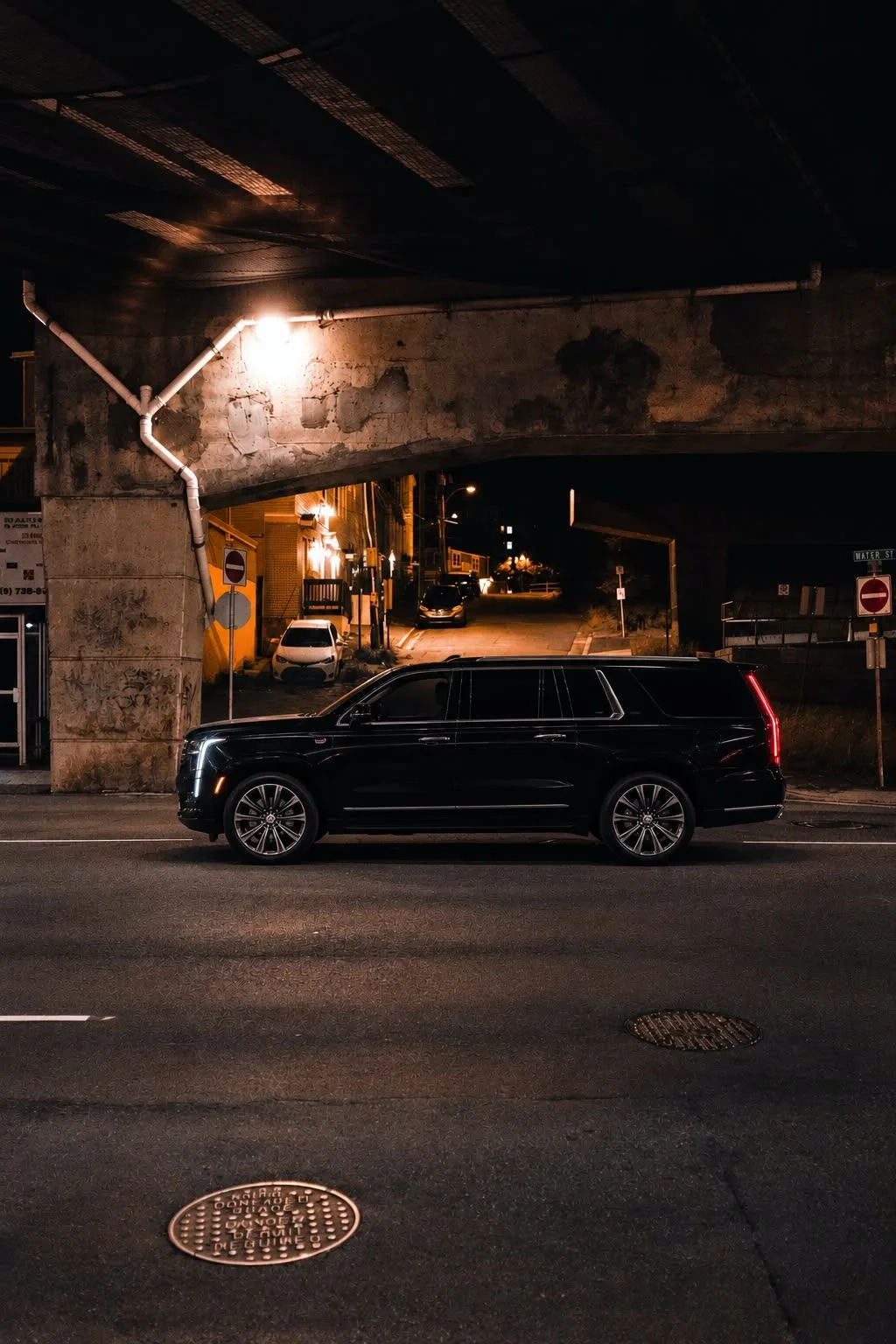 A black luxury sedan on a New York City street at dusk